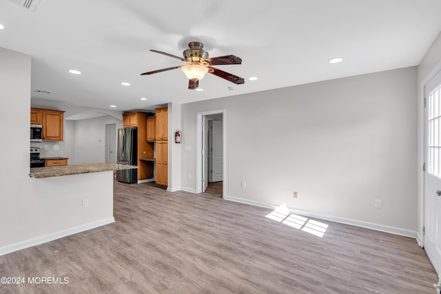 kitchen featuring ceiling fan, appliances with stainless steel finishes, light hardwood / wood-style floors, light stone counters, and kitchen peninsula