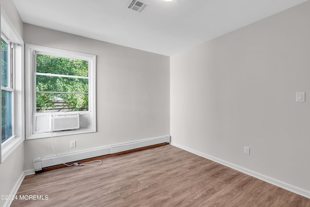 spare room with light hardwood / wood-style flooring, plenty of natural light, and a baseboard heating unit