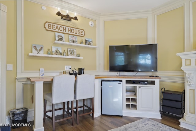 bar featuring stainless steel fridge, dark hardwood / wood-style floors, and ornamental molding