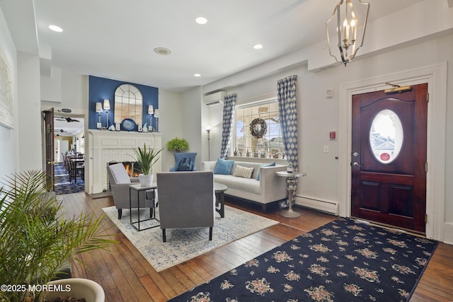 foyer with a baseboard heating unit, a wall mounted air conditioner, a chandelier, and hardwood / wood-style floors