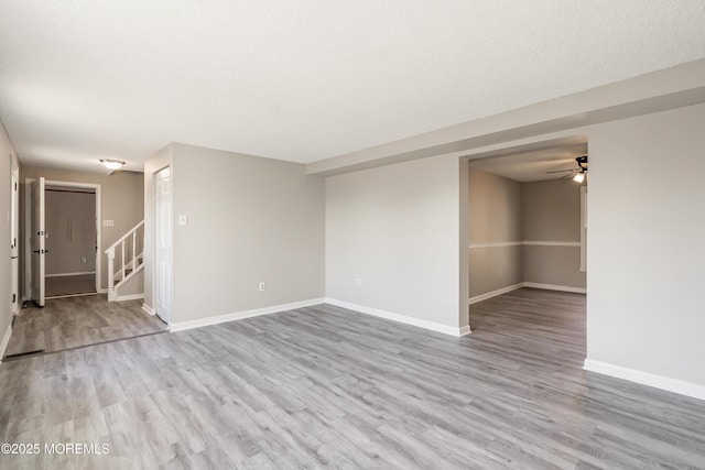 unfurnished room featuring light wood-type flooring, ceiling fan, and a textured ceiling