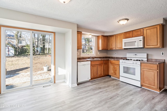 kitchen featuring a textured ceiling, sink, light hardwood / wood-style flooring, and white appliances