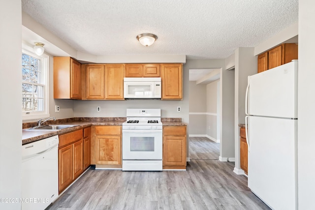 kitchen with sink, white appliances, a textured ceiling, and light wood-type flooring