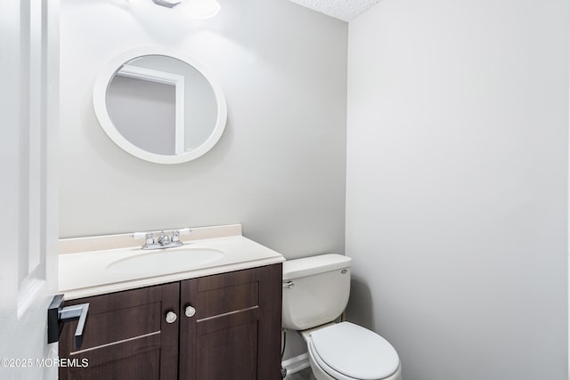 bathroom with toilet, a textured ceiling, and vanity