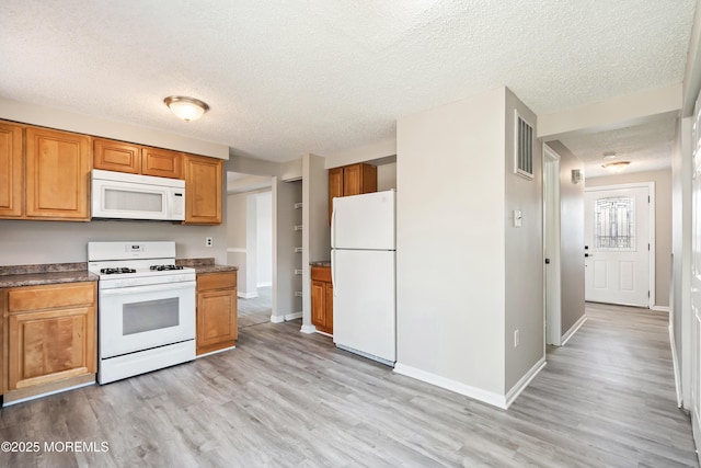 kitchen with light wood-type flooring, white appliances, and a textured ceiling