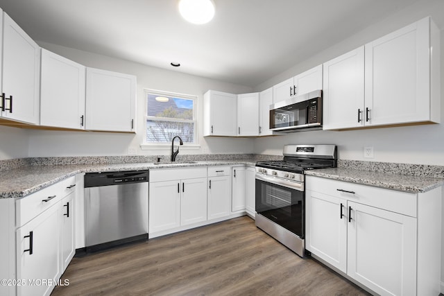 kitchen with white cabinets, appliances with stainless steel finishes, dark wood-type flooring, and sink