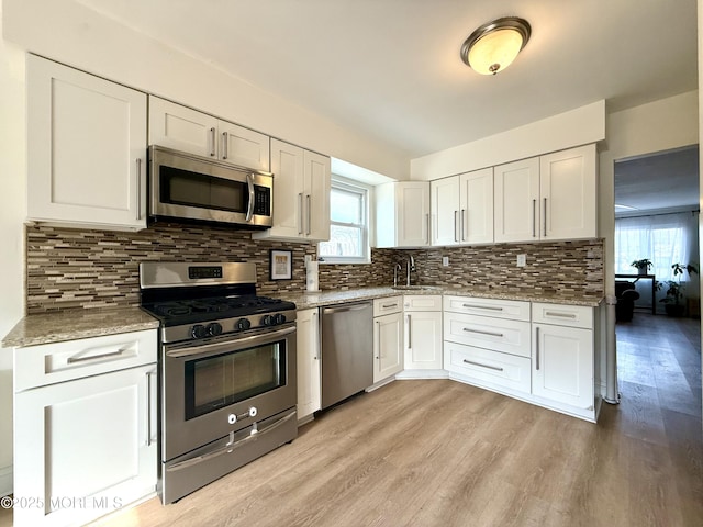 kitchen with decorative backsplash, sink, white cabinetry, and stainless steel appliances