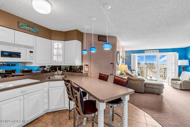 kitchen featuring a breakfast bar area, decorative light fixtures, white cabinetry, and kitchen peninsula