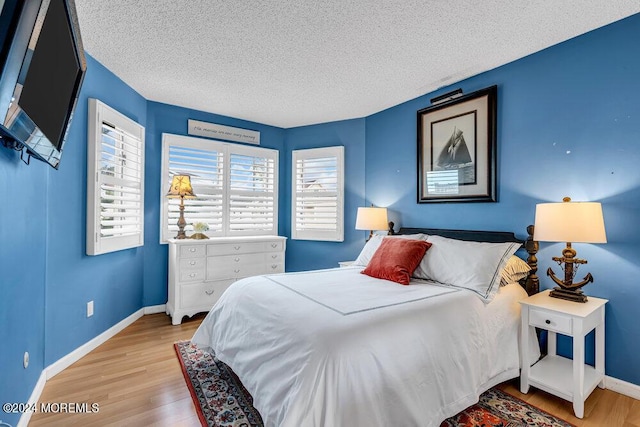 bedroom with a textured ceiling and light hardwood / wood-style flooring