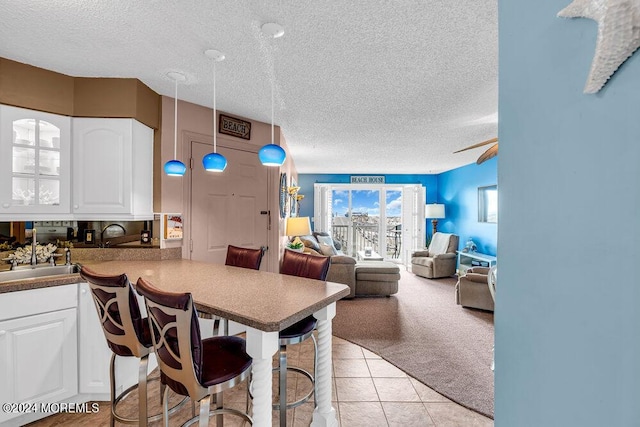 tiled dining space featuring a textured ceiling, ceiling fan, and sink