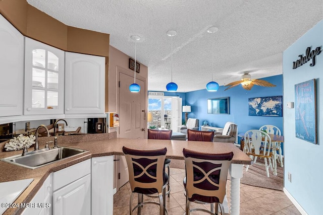 kitchen with sink, decorative light fixtures, white cabinetry, and light tile patterned flooring