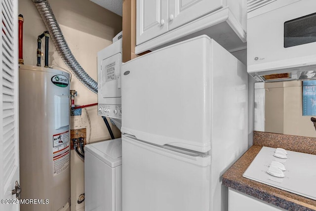 laundry area with cabinets, stacked washer / drying machine, and water heater