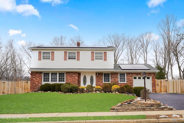 front facade featuring solar panels, a garage, and a front yard