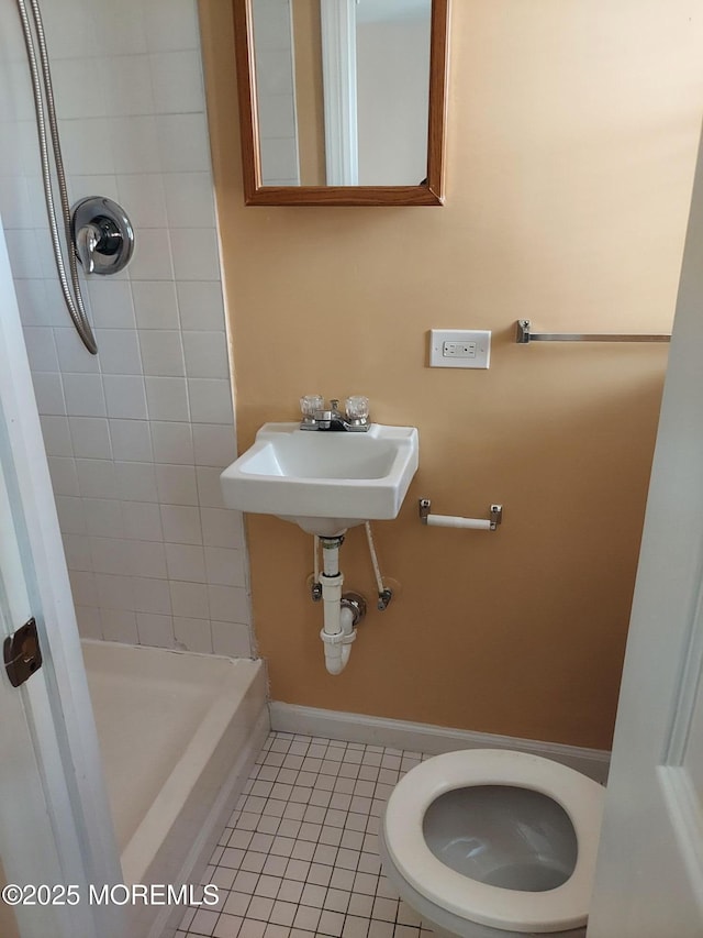 bathroom featuring tile patterned floors, sink, a tile shower, and toilet