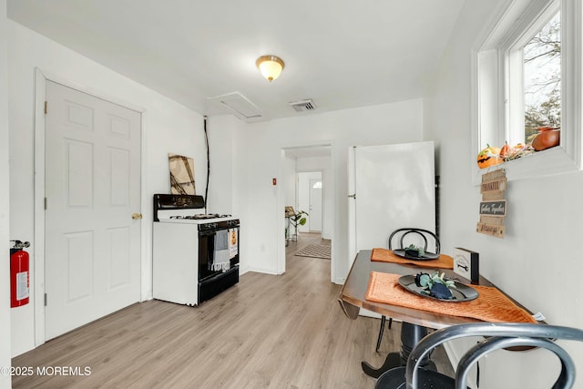 kitchen featuring light hardwood / wood-style floors, gas range, and white fridge