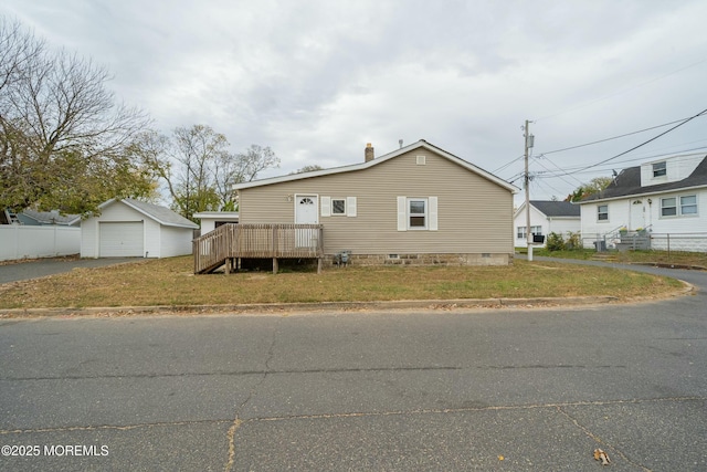 view of front of property with a front yard, a garage, a deck, and an outdoor structure