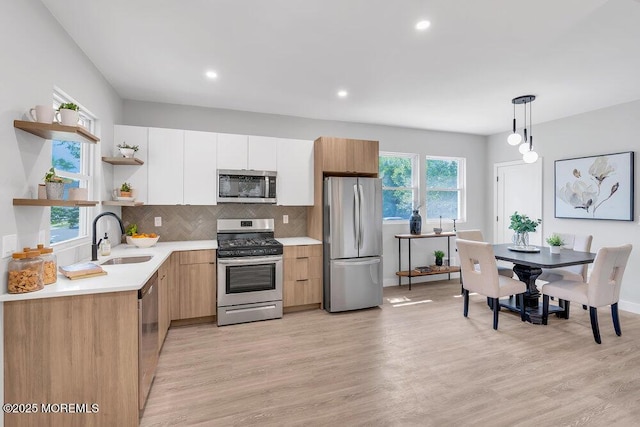 kitchen featuring pendant lighting, tasteful backsplash, white cabinets, appliances with stainless steel finishes, and sink