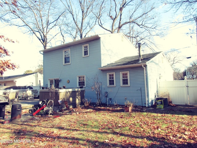 rear view of house with a wooden deck and a hot tub