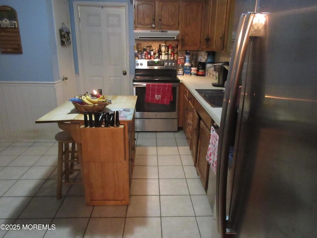 kitchen with a kitchen island, stainless steel appliances, sink, light tile patterned flooring, and a breakfast bar