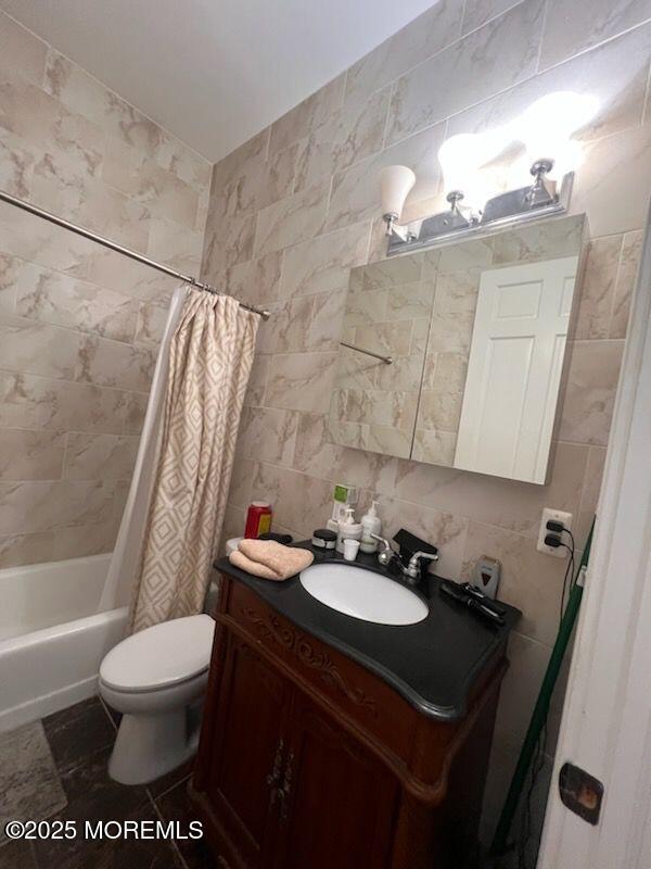 full bathroom with shower / tub combo, tasteful backsplash, vanity, tile walls, and toilet