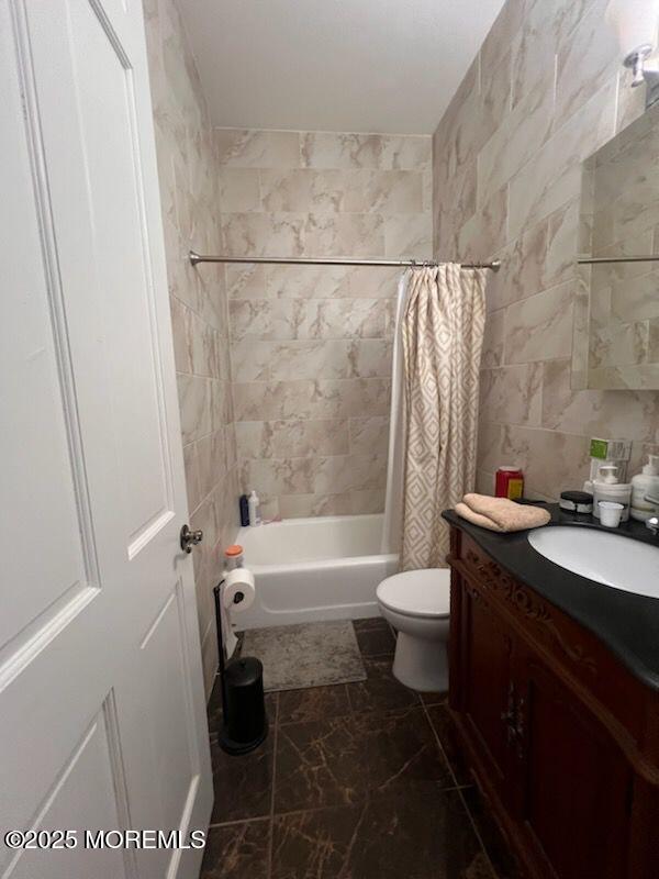 full bathroom with tile walls, vanity, shower / bath combo, and toilet