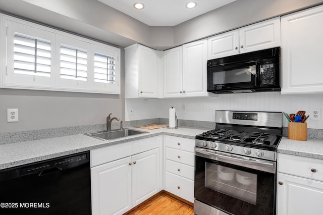 kitchen with black appliances, light wood-type flooring, white cabinetry, and sink