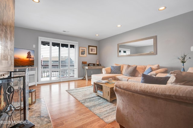 living room with a fireplace and light wood-type flooring