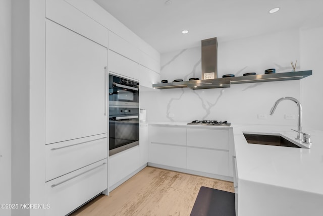 kitchen featuring sink, white cabinets, light hardwood / wood-style flooring, and ventilation hood