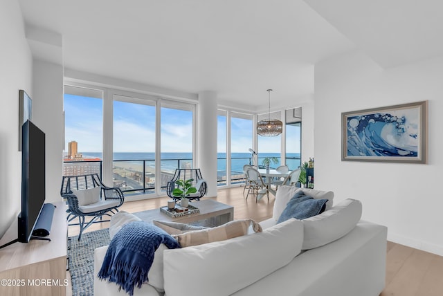 living room with light wood-type flooring, a water view, and floor to ceiling windows