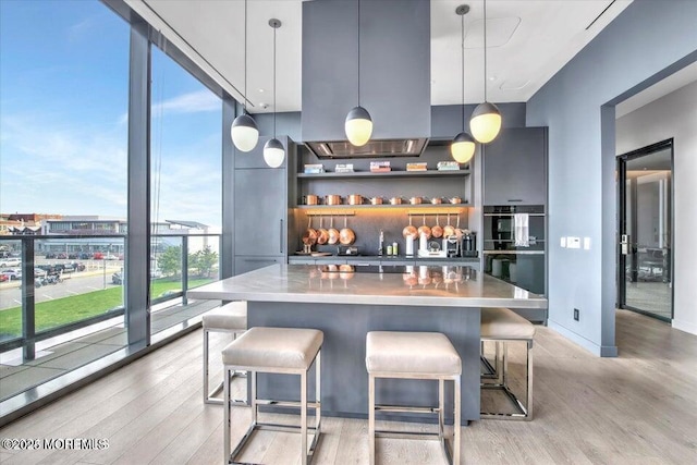 bar with light hardwood / wood-style flooring, expansive windows, and pendant lighting