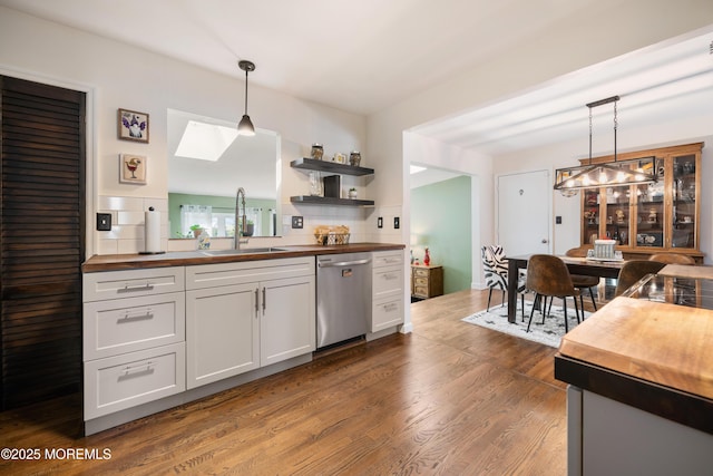 kitchen with wood counters, white cabinetry, pendant lighting, and dishwasher