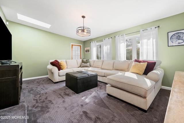 living room with a skylight and dark colored carpet