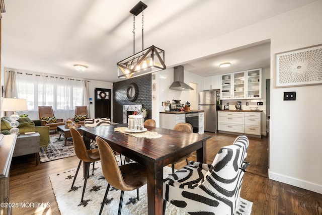 dining space with a brick fireplace and dark hardwood / wood-style floors