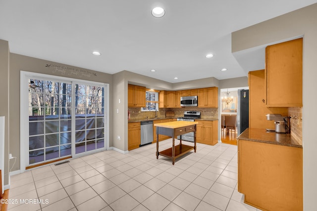 kitchen with sink, light tile patterned flooring, tasteful backsplash, and appliances with stainless steel finishes