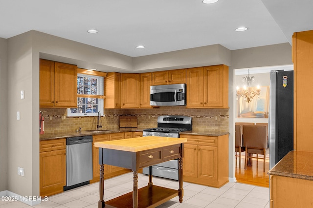 kitchen with appliances with stainless steel finishes, sink, light stone counters, and decorative backsplash