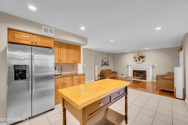 kitchen featuring stainless steel refrigerator with ice dispenser, decorative backsplash, and light tile patterned floors