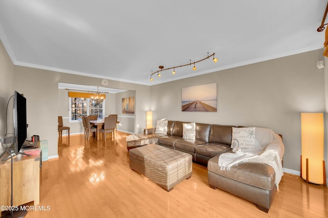 living room featuring light hardwood / wood-style flooring, an inviting chandelier, and crown molding