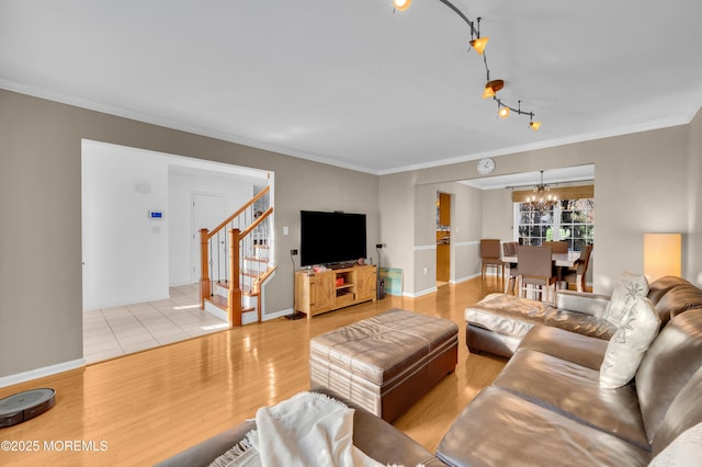 living room with light hardwood / wood-style floors, an inviting chandelier, and ornamental molding