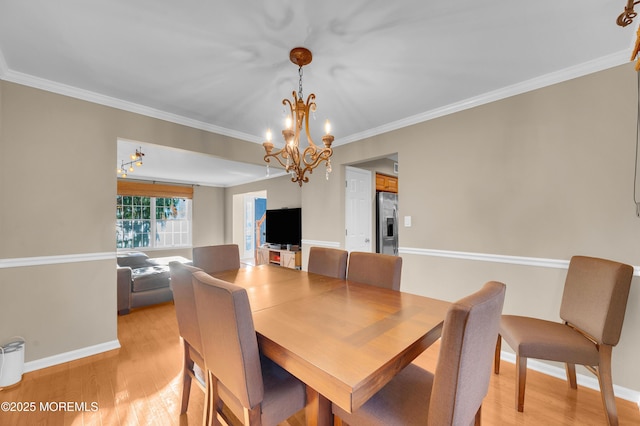 dining space featuring a chandelier, light wood-type flooring, and crown molding