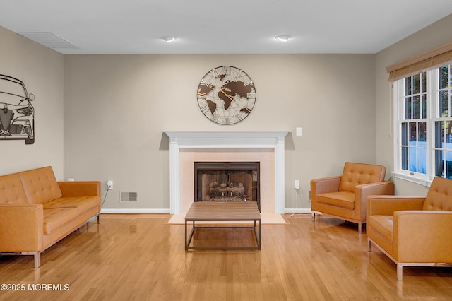 living area with a tiled fireplace and hardwood / wood-style floors