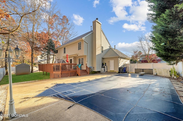 back of house featuring a patio area, a storage unit, and a wooden deck