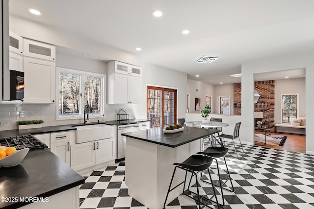 kitchen featuring sink, white cabinets, a center island, dishwasher, and a kitchen bar