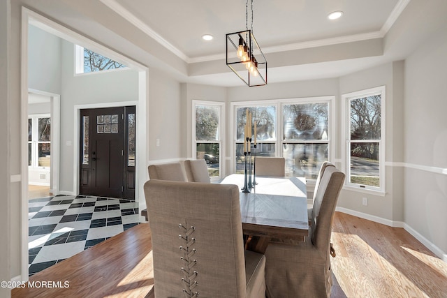 dining space featuring a raised ceiling, hardwood / wood-style flooring, and crown molding