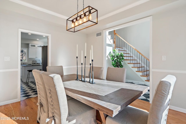 dining area featuring ornamental molding, light wood-type flooring, and an inviting chandelier