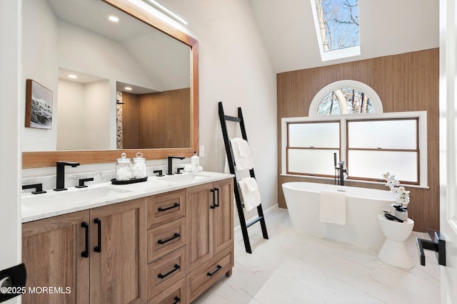 bathroom with a bath, lofted ceiling with skylight, and vanity