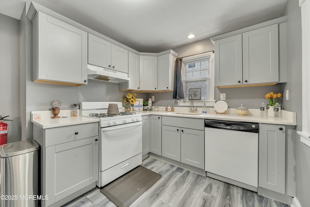 kitchen with light wood-type flooring, sink, white appliances, and white cabinetry