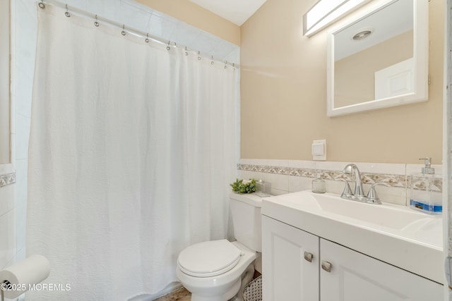 bathroom with toilet, tile walls, and vanity