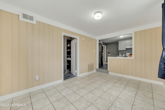 unfurnished living room featuring light tile patterned floors and crown molding