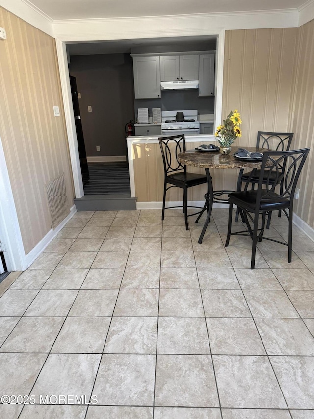 kitchen featuring light tile patterned flooring, ornamental molding, white gas range, and gray cabinets