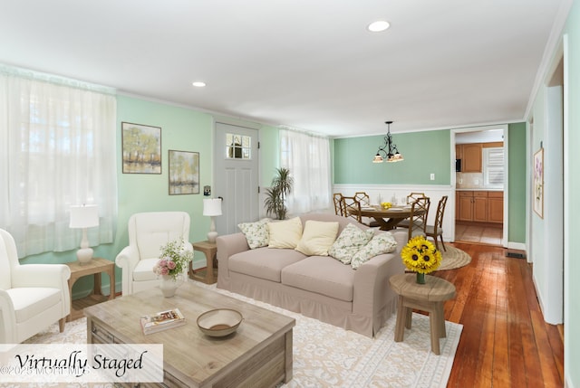 living room featuring an inviting chandelier, light wood-type flooring, and ornamental molding